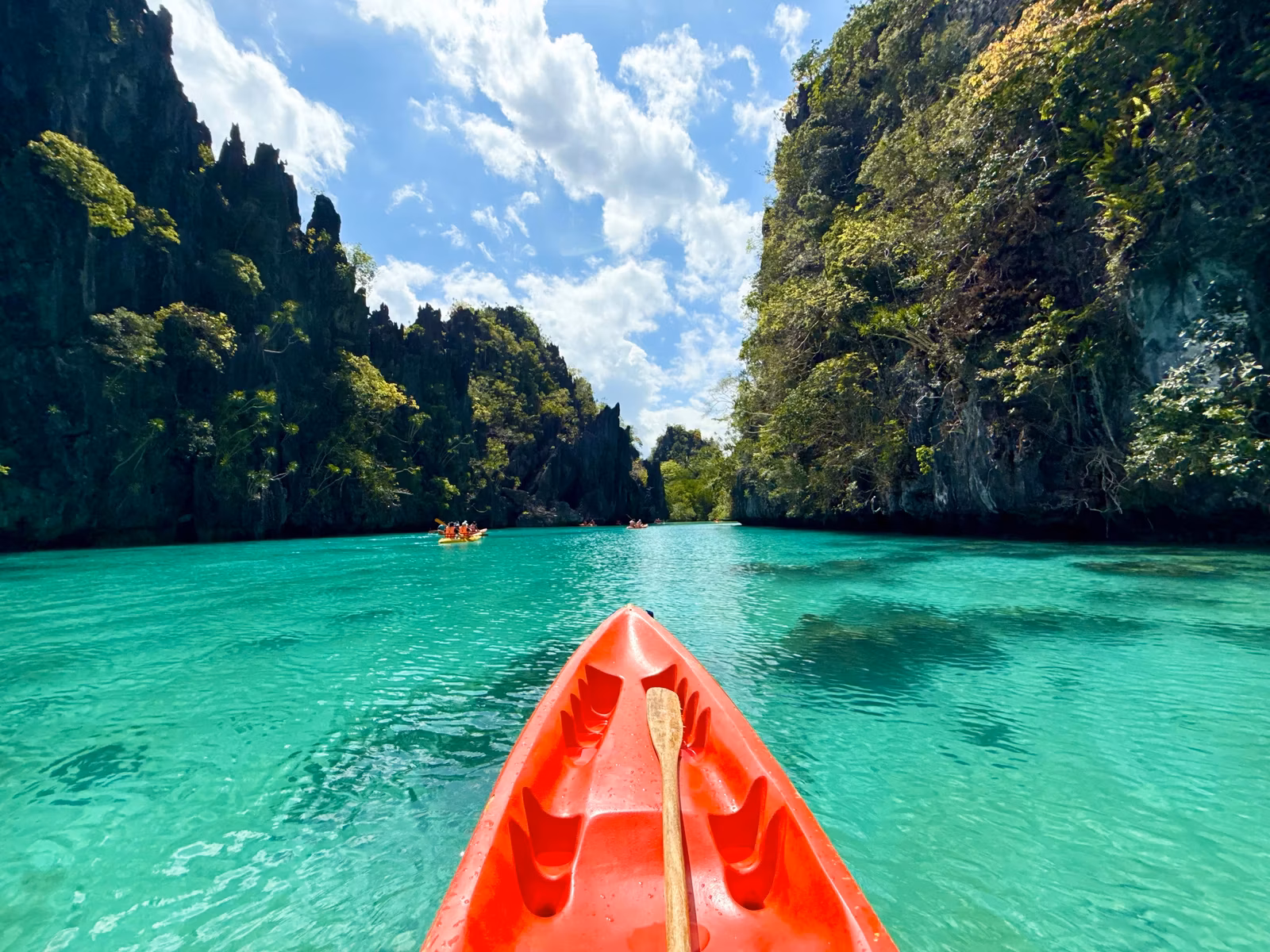Kayaking through clear turquoise water surrounded by dramatic mountains and islands