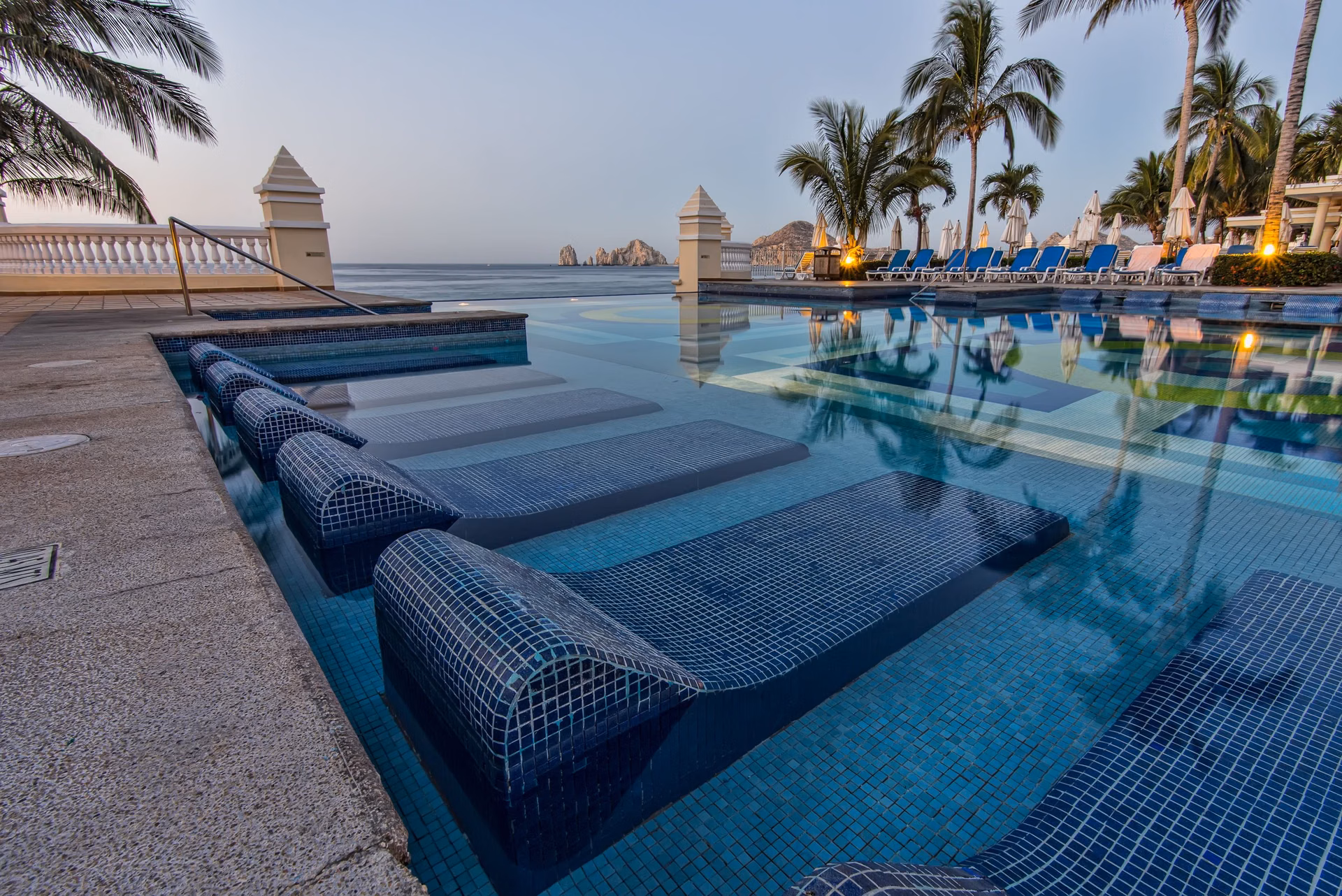 Blue sun loungers beside a resort pool, Chileno Bay amenities, Los Cabos